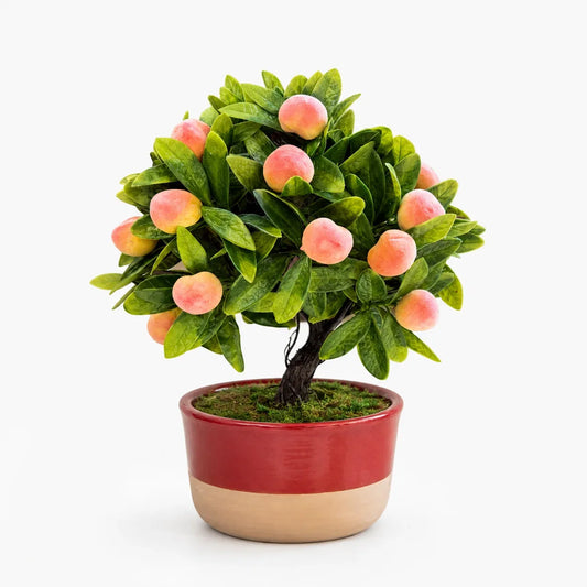 Artificial mini peach bonsai in a red and beige ceramic planter.